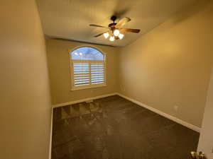 Empty room with dark carpet, a textured ceiling, and a ceiling fan