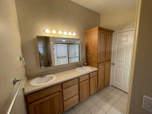 Full bathroom with double vanity and light tile patterned floors
