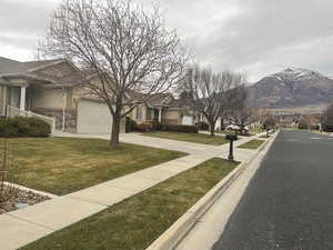 View of asphalt road with curbs, sidewalks, a residential view, and a mountain view