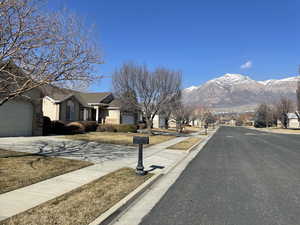 View of asphalt street featuring sidewalks, a residential view, curbs, and a mountain view