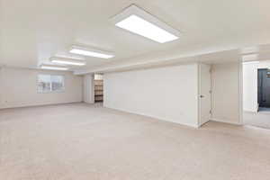 Basement featuring light carpet and baseboards