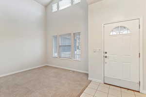 Foyer featuring light carpet, a high ceiling, and light tile patterned flooring