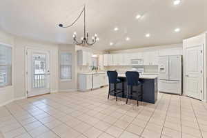 Kitchen featuring lofted ceiling, white appliances, light countertops, a breakfast bar, and a center island