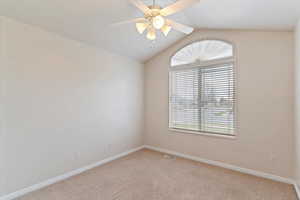 Carpeted spare room with ceiling fan and lofted ceiling