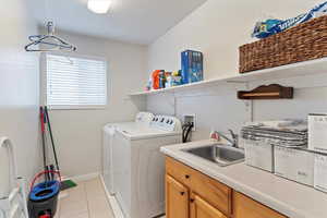 Laundry area with washer and clothes dryer and light tile patterned flooring