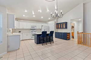 Kitchen featuring a kitchen breakfast bar, a center island, light countertops, white appliances, and glass insert cabinets