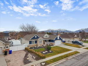 View of front of property with a residential view, stone siding, a mountain view, and concrete driveway