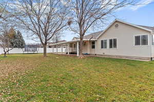 Rear view of house with a trampoline and stucco siding