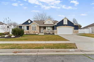 View of front of property featuring a porch, driveway, stone siding, a garage, and stucco siding