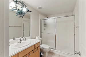 Bathroom featuring vanity, light tile patterned flooring, and a shower stall