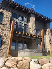Rear view of property featuring stone siding and a hot tub