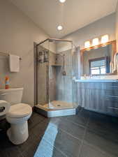 Full bath featuring vanity, dark tile patterned flooring, and a shower stall