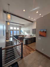 Kitchen with light countertops, beamed ceiling, recessed lighting, open floor plan, and dishwasher