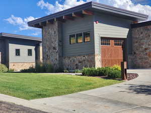 View of home's exterior featuring stone siding, a lawn, and an attached garage