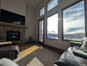Living room featuring wood finished floors, a mountain view, a high ceiling, and a stone fireplace