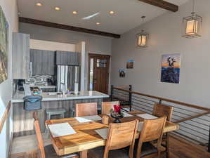 Dining room with beam ceiling, dark wood-type flooring, and recessed lighting