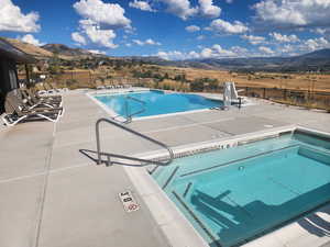 Community pool with a patio, a hot tub, and a mountain view