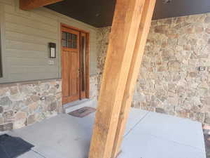 View of exterior entry with stone siding and a porch