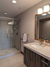 Bathroom with vanity, a stall shower, light tile patterned floors, and recessed lighting