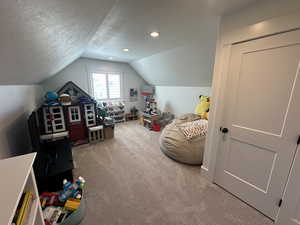 Bonus Room featuring a textured ceiling, lofted ceiling, and carpet flooring