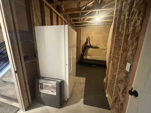 Unfinished basement with freestanding refrigerator