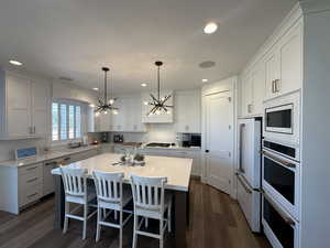 Kitchen with a chandelier, hanging light fixtures, white cabinets, a kitchen breakfast bar, and recessed lighting