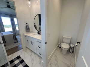 Primary Bathroom featuring light marble finish flooring, vanity, and a ceiling fan