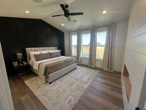 Primary Bedroom featuring vaulted ceiling, a decorative wall, dark wood-style floors, ceiling fan, and recessed lighting