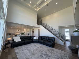 Living area featuring recessed lighting, dark wood-style flooring, stairs, and a high ceiling