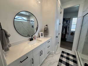 Primary Bathroom with light marble finish floors, vanity, a marble finish shower, and a walk in closet