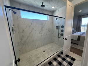 Primary Bathroom featuring light marble finish floors, a marble finish shower, and connected bathroom