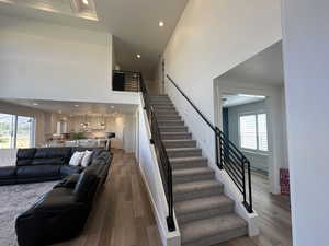 Staircase with wood finished floors, a high ceiling, and recessed lighting