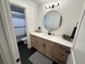 Full bathroom with a shower with shower curtain, vanity, and dark tile patterned flooring