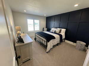 Bedroom featuring a decorative wall, light colored carpet, and recessed lighting