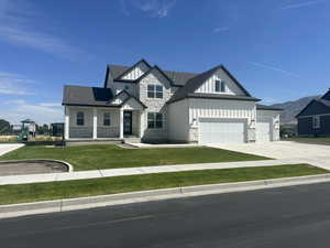 View of front of house with board and batten siding, stone siding, a front yard, a porch, and driveway