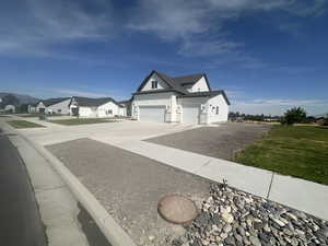 View of property exterior with board and batten siding, concrete driveway, a lawn, and a residential view
