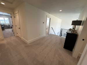 Hallway with an upstairs landing, recessed lighting, and carpet flooring