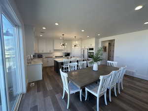 Dining room with dark wood finished floors, recessed lighting, and a chandelier