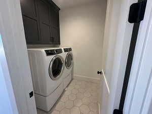Laundry room with light tile patterned floors, washer and dryer, and cabinet space