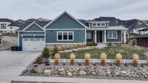 Craftsman-style home featuring covered porch, board and batten siding, driveway, stone siding, and a garage