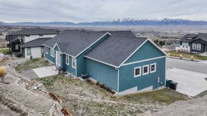 North side view of property exterior with a shingled roof, a mountain view, and stucco siding