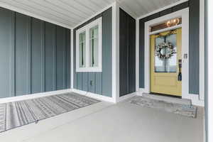 Doorway to property with board and batten siding and a porch