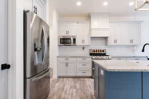 Kitchen featuring stainless steel appliances, granite countertops, white cabinetry, and recessed lighting