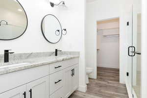 Bathroom with a spacious closet, double vanity, and light wood-style flooring