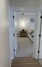 Photos are of staged model home. Hallway featuring baseboards and light wood-style flooring entering Primary Suite