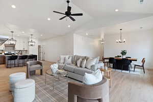 Living area with suspended lighting, light wood-style floors, a ceiling fan, and lofted ceiling