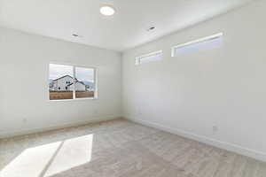 Empty room featuring plenty of natural light and light colored carpet