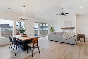 Dining area featuring light wood-style flooring, lofted ceiling, a chandelier, and ceiling fan