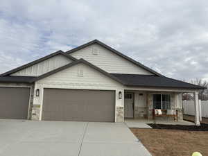 Craftsman-style home featuring stone siding, driveway, and an attached garage