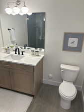 Photos are of staged model home.  Secondary Suite Bathroom with vanity, dark wood-type flooring, and a shower stall